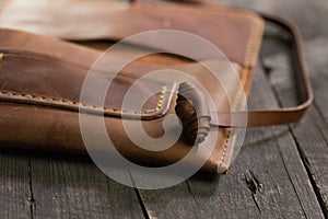 Brown fashion tobacco pouch leather on wood background. Craft product handmade.