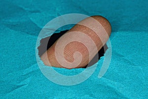 brown finger in a hole in a piece of blue paper