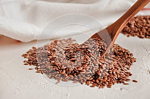 Brown flax seed background. Linseed grain wooden spoon texture. Flaxseed oil preparation.