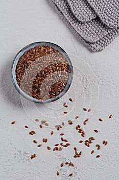 Brown flax seed or linseed in small bowl on a light gray background
