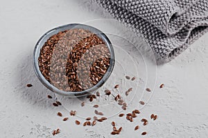 Brown flax seed or linseed in small bowl on a light gray background