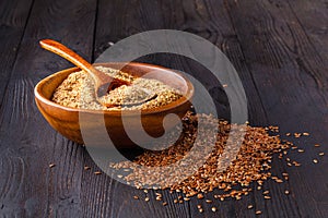 Brown flax seeds on spoon and flaxseed oil in glass jug on wooden table. Flax oil is rich in omega-3 fatty acid.