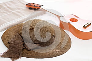 Brown floopy hat with ribbon, little guitar toy and towel background. Summer holiday concept