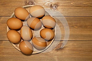 Brown fresh chicken eggs in  wooden plate on wood backdgound. Organic rural products concept