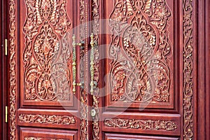 Brown front door with a pattern of wood carvings.