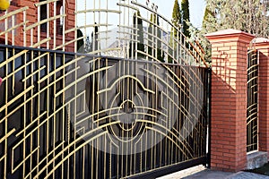 Brown gate and metal fence with forged pattern on the street