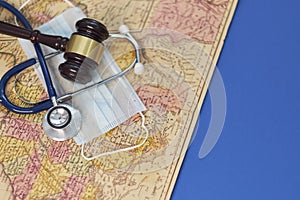 Brown gavel and a medical stethoscope and a protective mask on a geographical map. symbol photo for bungling and medical