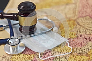 Brown gavel and a medical stethoscope and a protective mask on a geographical map. symbol photo for bungling and medical
