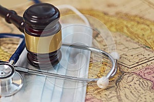 Brown gavel and a medical stethoscope and a protective mask on a geographical map. symbol photo for bungling and medical