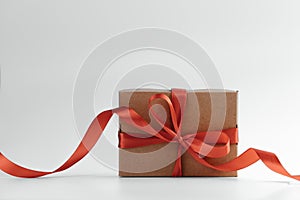 Brown gift box with red bow and ribbon on white background.