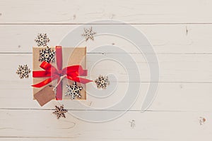 Brown gift box and snowflakes on white wooden background. Vintage gift box on wooden background. Gift box with red ribbon on wood