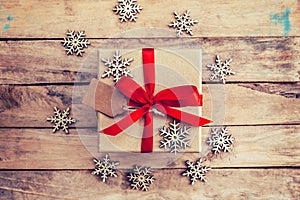 Brown gift box and snowflakes on wooden background. Vintage gift