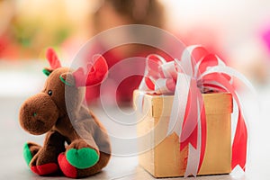 A brown gift box tied with a red and white ribbon was placed on the ground and a reindeer doll