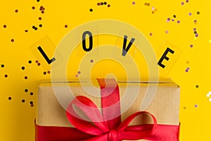 Brown gift boxes with red ribbons. Word Love. Yellow background with multicolored confetti. Flat lay style. Gift for Mother day or