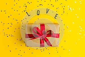 Brown gift boxes with red ribbons. Word Love. Yellow background with multicolored confetti. Flat lay style. Gift for Mother day or