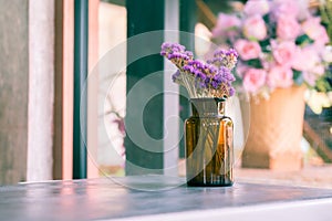 Brown glass bottle with dried pink and purple flower on table in