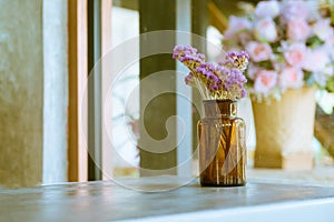 Brown glass bottle with dried pink and purple flower on table in