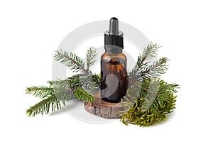 Brown glass bottle of essential oil and twig of fir tree on white