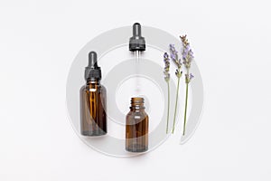 Brown glass bottles with pipette with lavender essence oil, lavender flowers on white background top view. Natural cosmetics with