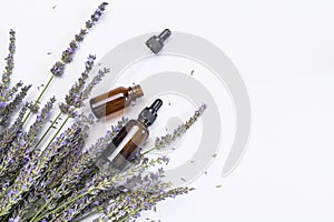 Brown glass bottles with pipette with lavender essence oil, lavender flowers on white background top view. Natural cosmetics with