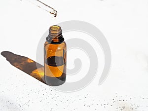 Brown glass with a dropper and a drop of essence. Bottle mockup cosmetic oil dropper on a glass pipette. Copy space