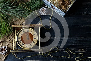Brown and golden vintage clock, pine branches on black background. Merry Christmas, Happy New Year eve, winter holidays