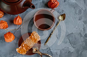 Brown Grape sugar in clear crystals, tea and tongs on grey slate close-up. Oriental sweetness to tea