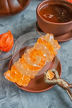 Brown Grape sugar in clear crystals, tea and tongs on grey slate close-up. Oriental sweetness to tea