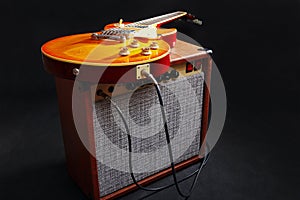 Brown guitar amplifier with honey sunburst guitar on black background