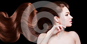 Brown Hair. Beautiful young woman with healthy luxurious long hair on dark background. Hairstyle. Hair cosmetics