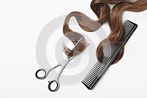 Brown hair, comb and thinning scissors on white background, top view.