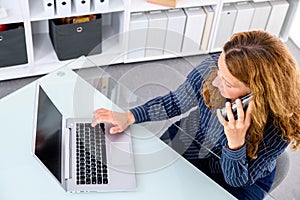 Brown-haired blond businesswoman with computer and phone