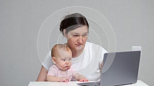 Brown-haired freelancer works on laptop with baby daughter