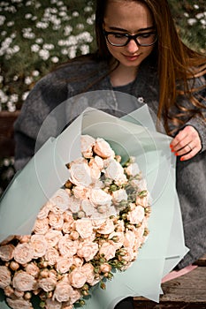 brown haired girl admires huge pink rose bouquet