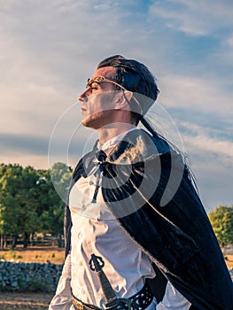 Brown-haired man with elf ears, tiara on head and black cape, looks forward