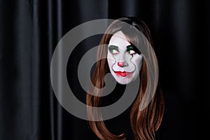 Brown haired woman clown with green eyes on a black background for Halloween