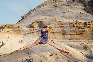 Brown-haired woman in purple glittering dress dancing on sand