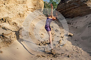 Brown-haired woman in purple glittering dress dancing on sand