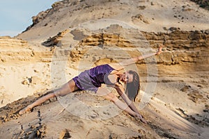 Brown-haired woman in purple glittering dress dancing on sand