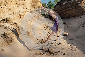 Brown-haired woman in purple glittering dress dancing on sand