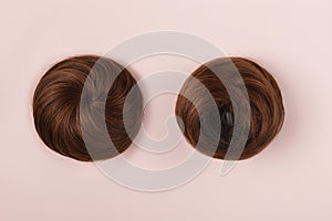 A brown hairpiece on the pink background. Flat-lay.