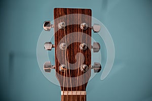 Brown headstock of guitar on a turquoise background