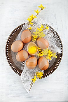 Brown hen`s eggs decorates with yellow flowers on antique plate, rustic food photography
