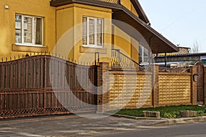 Brown iron gate and a brick fence in the street in front of the house