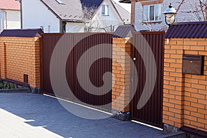 Brown iron gate and brick fence on the street at the sidewalk