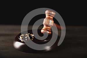 Brown judje wooden gavel and wedding rings on the table. Divorce process concept.