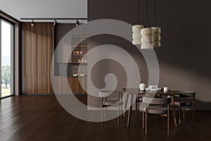 Brown kitchen interior with eating table and cooking area near panoramic window