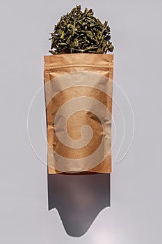 Brown kraft paper pouch bags with tea leaves top view with harsh shadow on white background. Coffee packaging flat lay