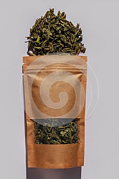 Brown kraft paper pouch bags with tea leaves top view with harsh shadow on white background. Coffee packaging flat lay