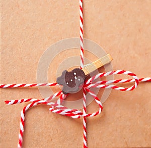 Brown kraft paper texture with striped ribbon and gingerbreadman clothpin for packaging or gift wrapping. Kraft paper texture